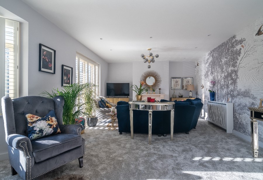 Spacious family living room with woodland mural wallpaper, mirrored oval coffee table, grey buttoned wingback chair, Sputnik chandelier and indoor palm — interior design Princes Risborough Buckinghamshire