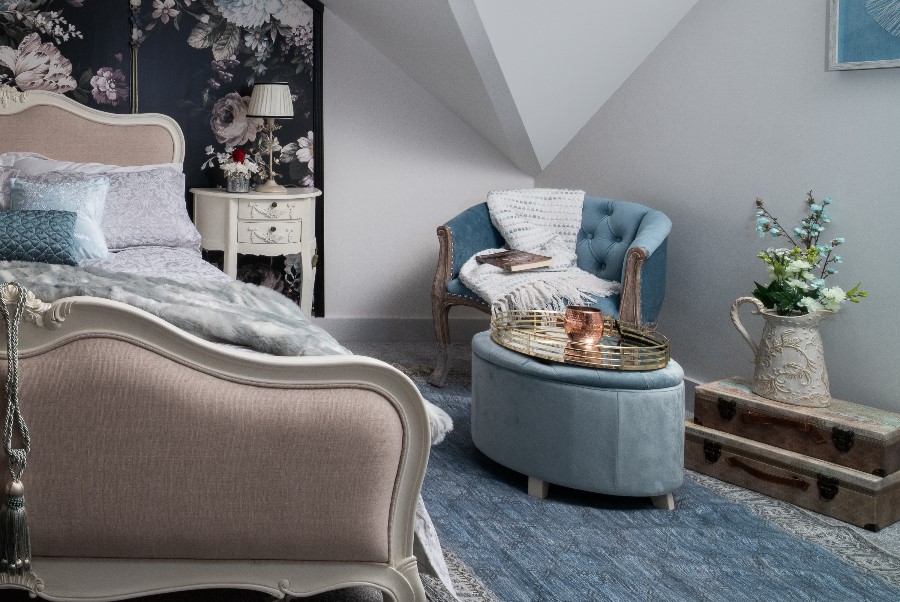 Master bedroom with dark dramatic floral wallpaper, French carved bed frame, duck egg blue tub chair and ottoman, geometric painted ceiling and vintage trunk — residential interior design Princes Risborough Buckinghamshire