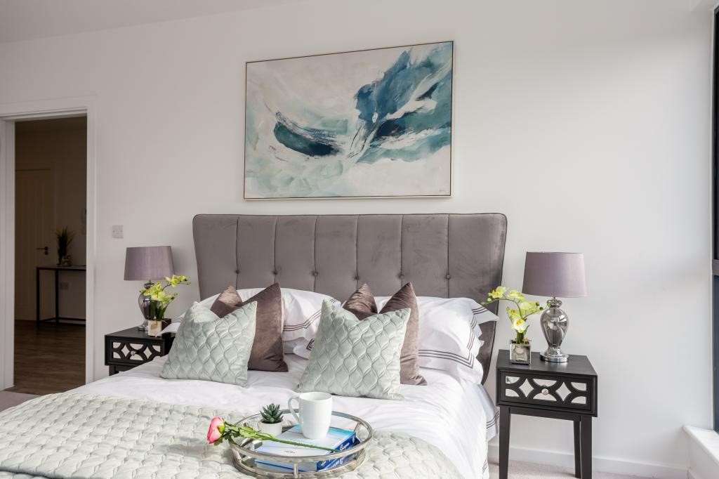 Penthouse master bedroom with tall grey buttoned velvet headboard, teal abstract painting, mauve lamps and orchid bedside styling — property styling Gerrards Cross Buckinghamshire