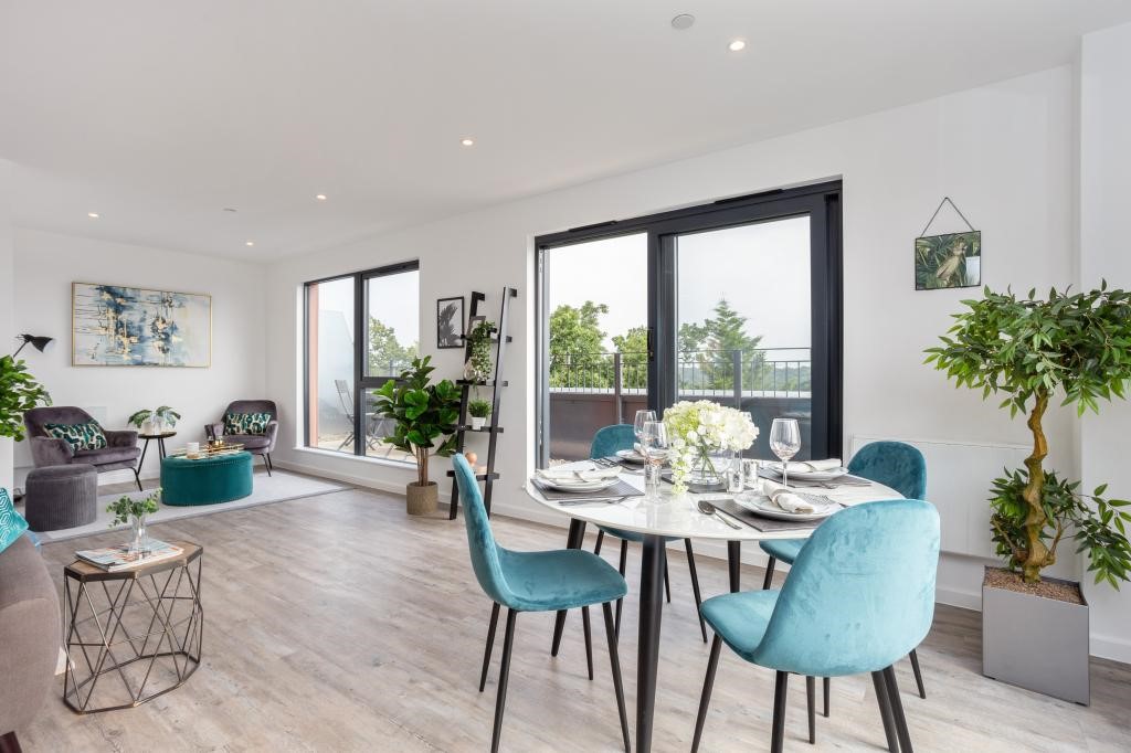 Open-plan penthouse living and dining area with teal velvet chairs, marble dining table, indoor plants and balcony views over treetops — interior design Gerrards Cross
