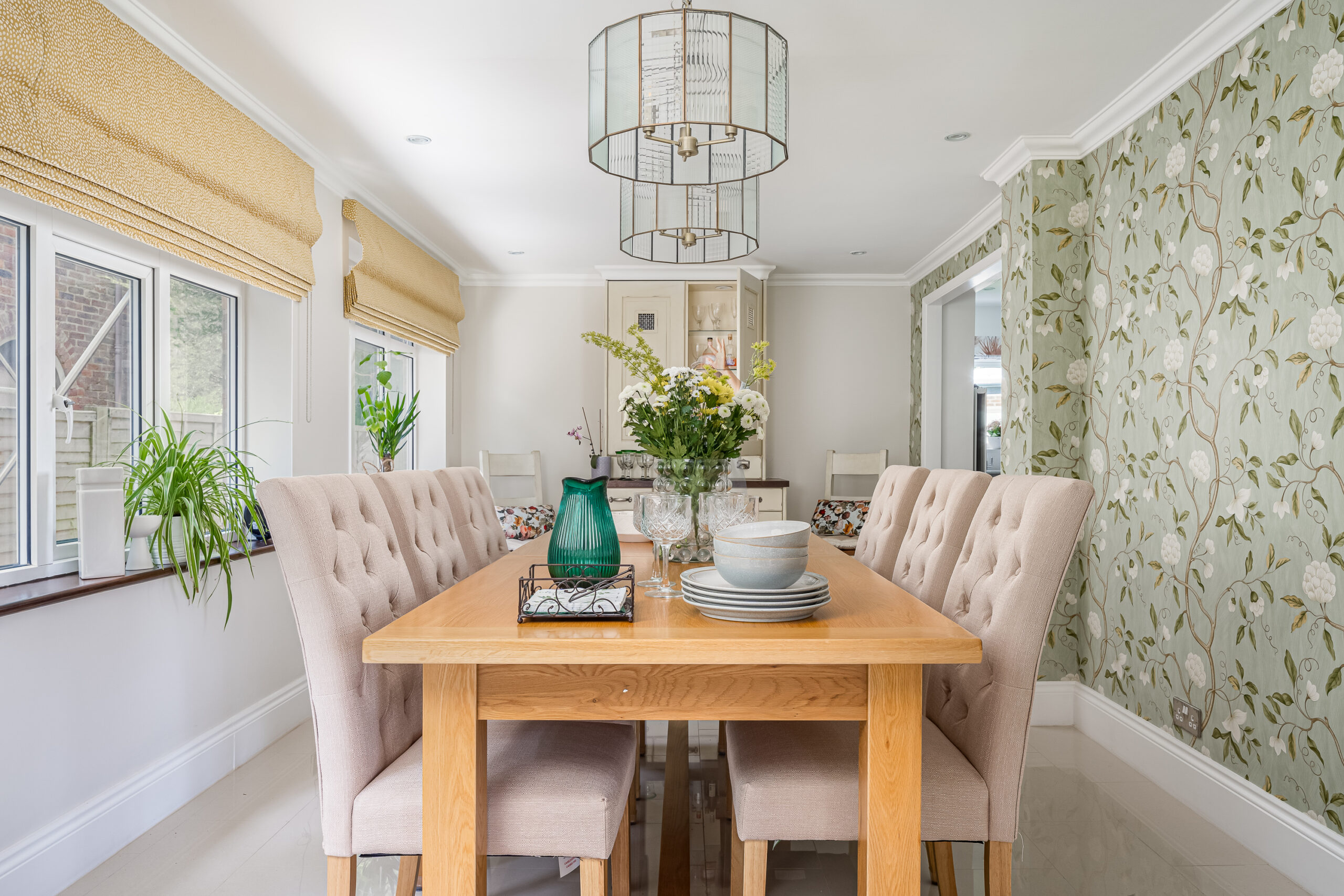 Dining room with sage green botanical wallpaper, reeded glass brass pendant light, buttoned linen chairs and solid oak table — family home interior design Penn Buckinghamshire