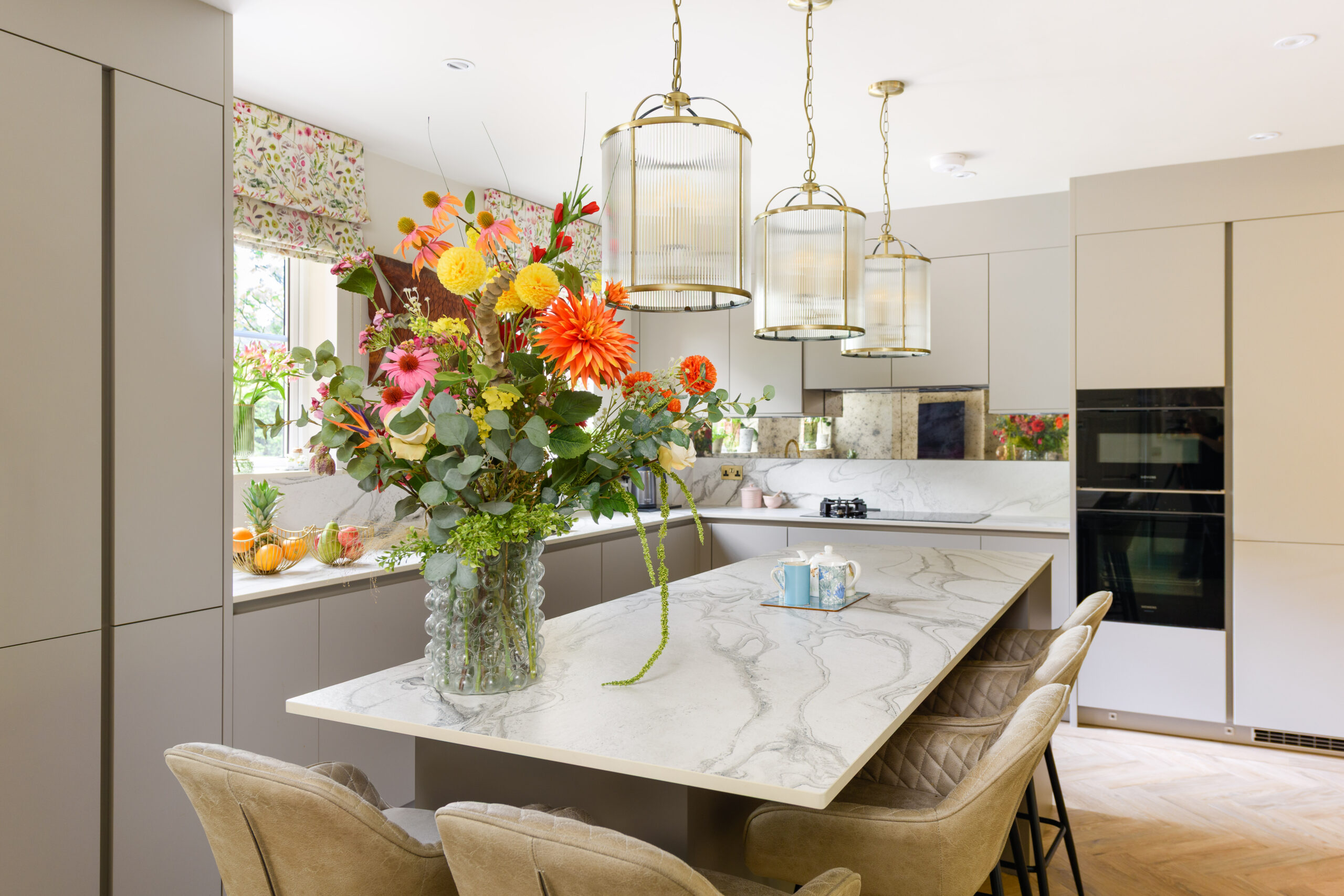 Open-plan family kitchen with Dekton island, leather bar stools, brass lantern pendants and herringbone oak LVT floor — residential interior design Buckinghamshire