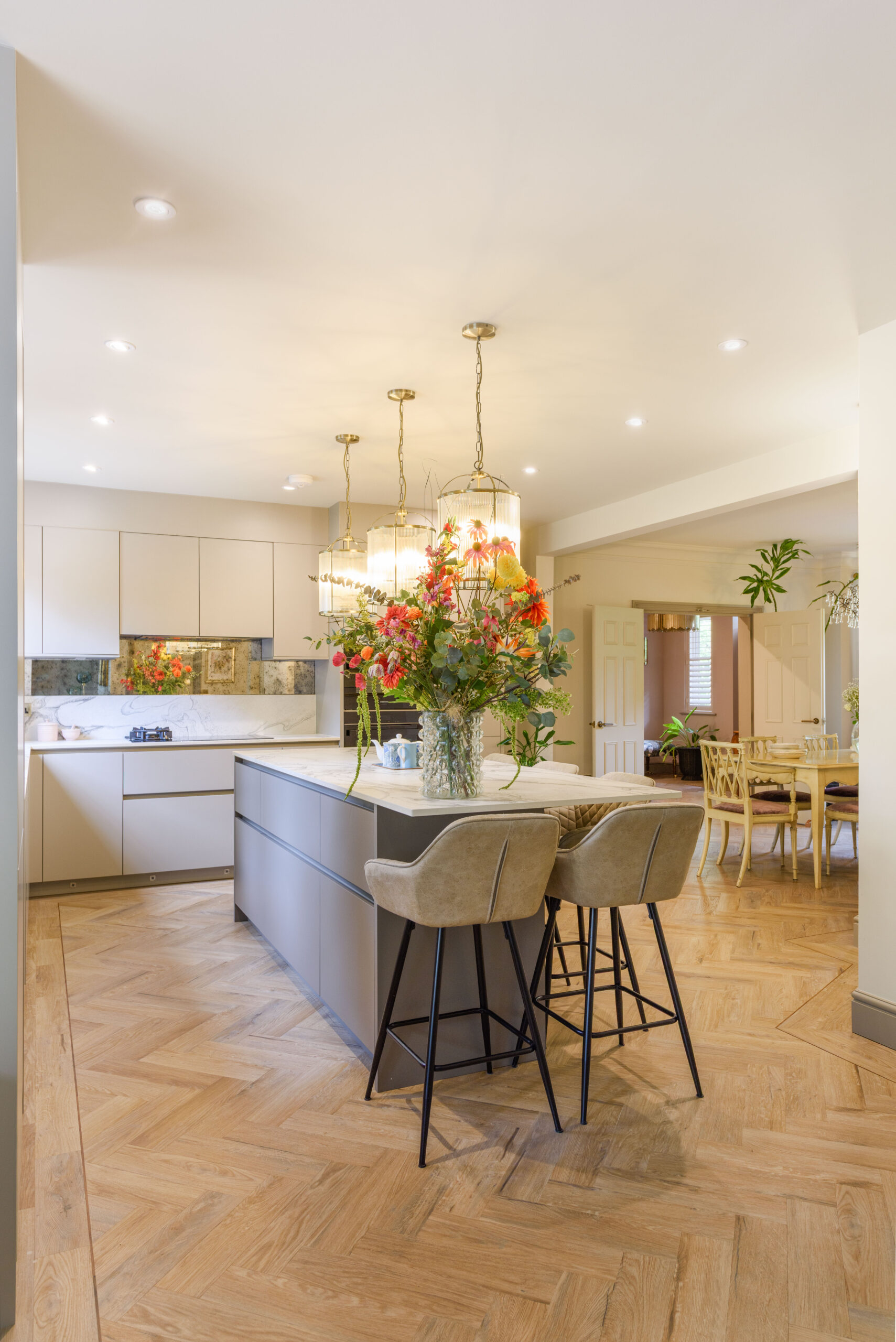 Open-plan kitchen and dining room with wide herringbone LVT floor, dekton island and brass pendants — family interior design Buckinghamshire